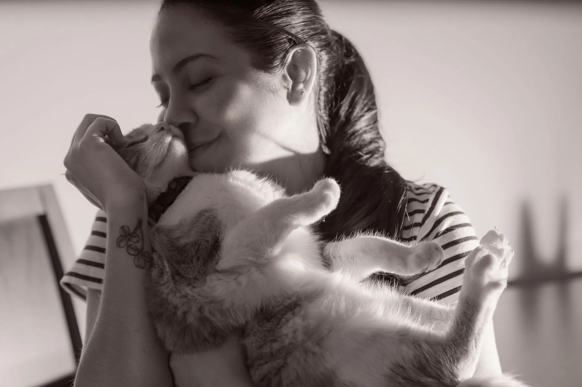 Tutora abraçando e beijando o seu gato no colo