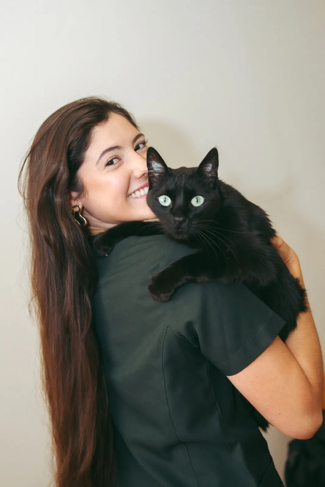 Dra. Clara Gomez Scarpelli sorrindo com um gato preto apoiado no ombro
